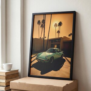 Peut inclure: Une impression d'art encadrée représentant une voiture de sport vintage vert clair garée devant un bâtiment moderne au coucher du soleil. La scène montre de grands palmiers en silhouette sur un ciel orange chaud, avec de longues ombres au sol.