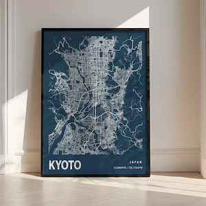 Peut inclure: Une impression encadrée d'une carte de Kyoto, au Japon, dans un style minimaliste. La carte présente des lignes blanches sur un fond bleu foncé, avec le nom de la ville et les coordonnées en bas. Le cadre est noir.