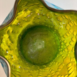 May include: A top-down view of a glass vase featuring a vibrant lime green interior with a textured, bubbled surface. The rim has a wavy, scalloped edge, and the exterior transitions into a bright turquoise blue color with a matching bubbled pattern.
