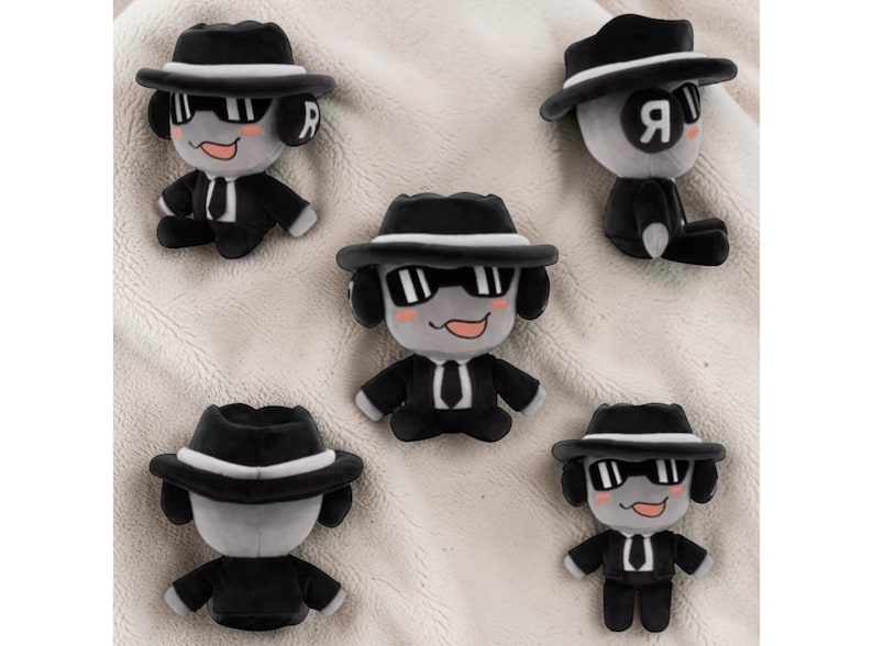 May include: Several plush dog toys dressed in black suits, fedora hats, and sunglasses. The toys are grey and black, with a smiling face and the letter "R" on the side of the head. The toys are arranged on a soft, white surface.