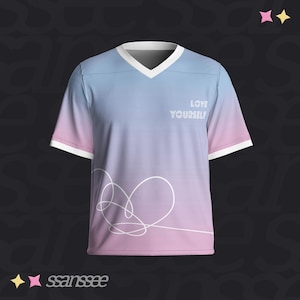 Peut inclure: Un t-shirt à col en V à manches courtes avec un dégradé bleu et rose. Le t-shirt présente une bordure blanche sur le col et les manches, avec les mots "LOVE YOURSELF" imprimés sur la poitrine. Un motif de cœur blanc est sur le bas du devant.