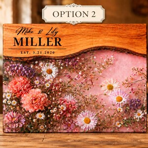 May include: A wooden block with a floral arrangement encased in resin. The top section is wood with the names "Mike & Lily MILLER" and the date "EST. 3.21.2020" printed on it. The flowers are pink, white, and purple.