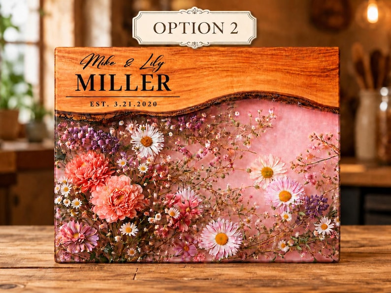 May include: A wooden block with a floral arrangement encased in resin. The top section is wood with the names "Mike & Lily MILLER" and the date "EST. 3.21.2020" printed on it. The flowers are pink, white, and purple.