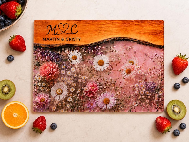 May include: Rectangular cutting board with a floral design and the text "M♡C MARTIN & CRISTY". The board features a wood-grain top and a pink floral pattern with daisies and other flowers. Strawberries, blueberries, kiwi, and an orange slice surround the board.