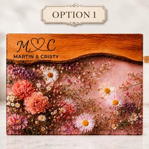 May include: A rectangular wooden plaque with a live edge, featuring embedded flowers in shades of pink, white, and purple. The top section has the text "OPTION 1" and the names "MARTIN & CRISTY" with initials "M & C" in a heart.