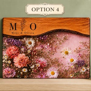 May include: A rectangular wooden plaque with a live edge, featuring the text "M O" and "Mike & Olivia". The lower portion is filled with dried flowers in shades of pink, purple, and white, set against a pink background. The plaque is labeled "OPTION 4".