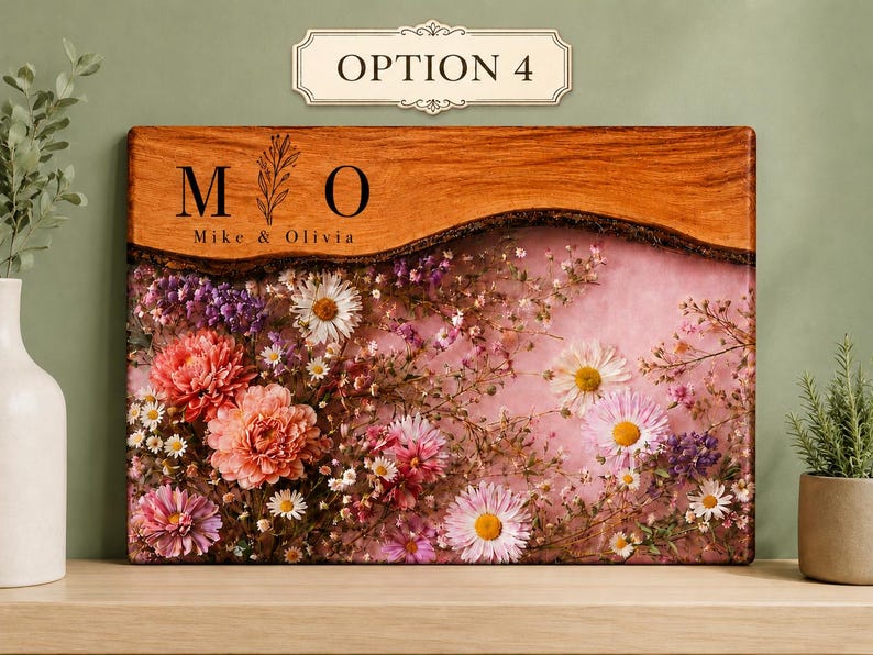 May include: A rectangular wooden plaque with a live edge, featuring the text "M O" and "Mike & Olivia". The lower portion is filled with dried flowers in shades of pink, purple, and white, set against a pink background. The plaque is labeled "OPTION 4".