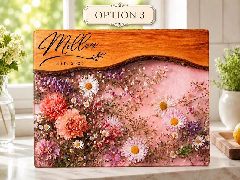May include: A rectangular wooden cutting board with a live edge, featuring a floral design with pink, purple, and white flowers encased in resin. The top section has the word "Miller" and "EST. 2026" in black script.