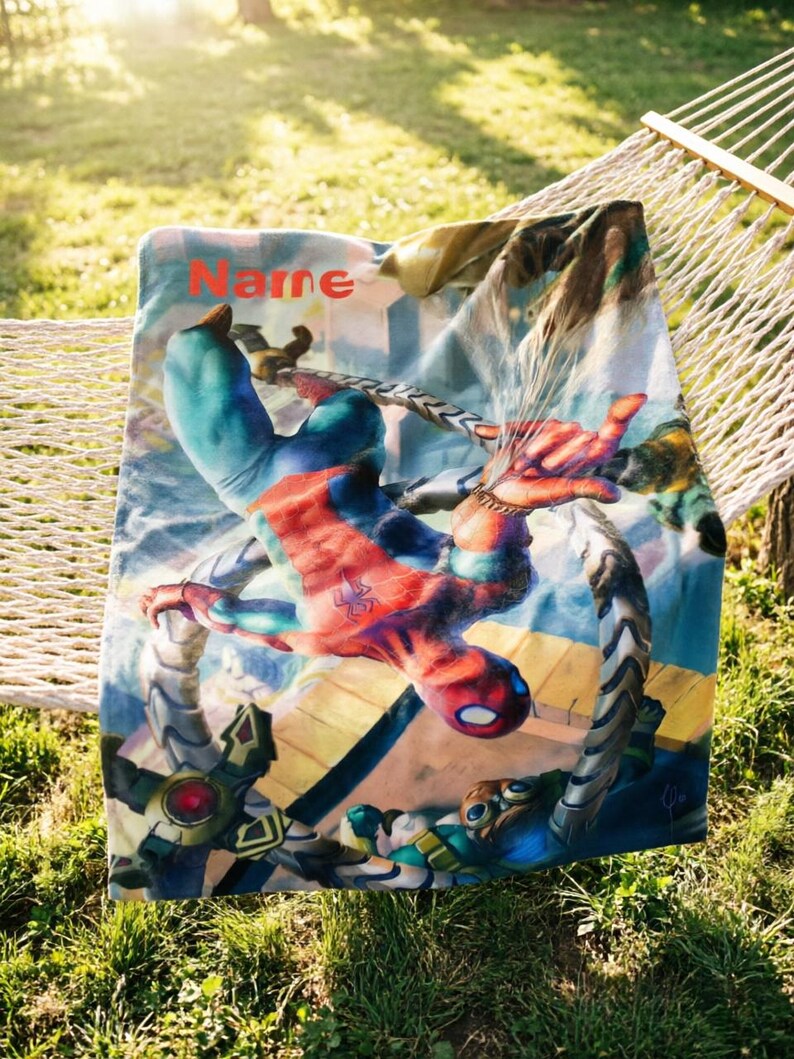 May include: A rectangular fleece blanket featuring a vibrant graphic of the superhero Spider-Man in a dynamic action pose against a city backdrop, with the word Name printed in red at the top left corner and mechanical tentacles visible below.