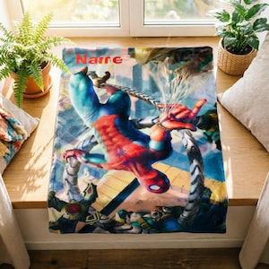 May include: A rectangular fleece blanket featuring a vibrant graphic of Spider-Man in a red and blue suit, suspended by mechanical tentacles. The word Name is printed in orange at the top. The design includes detailed action imagery of the character.
