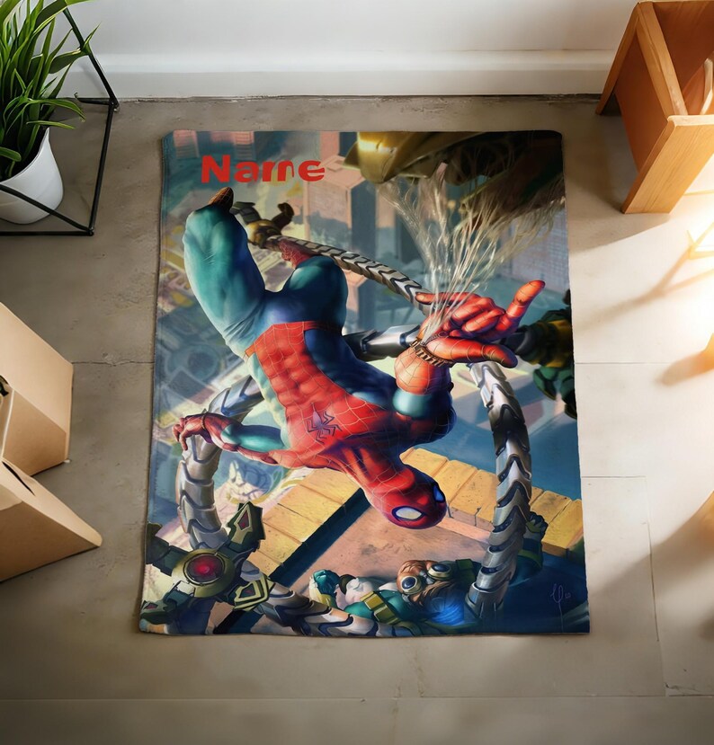 May include: A rectangular blanket featuring a vibrant graphic print of Spider-Man in a red and blue suit battling Doctor Octopus with his mechanical tentacles. The word Name is printed in red at the top center of the design against a city background.