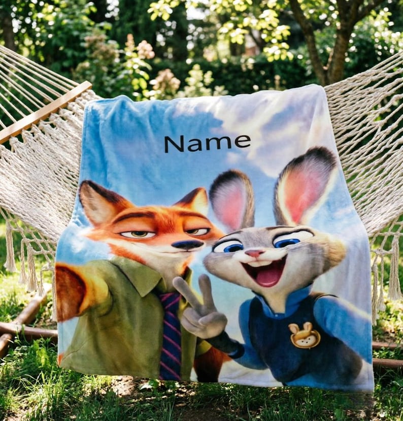 May include: A blue blanket featuring Nick Wilde and Judy Hopps from Zootopia, with the word "Name" printed on it. The blanket is draped over a hammock in a garden setting. The characters are in a selfie pose.