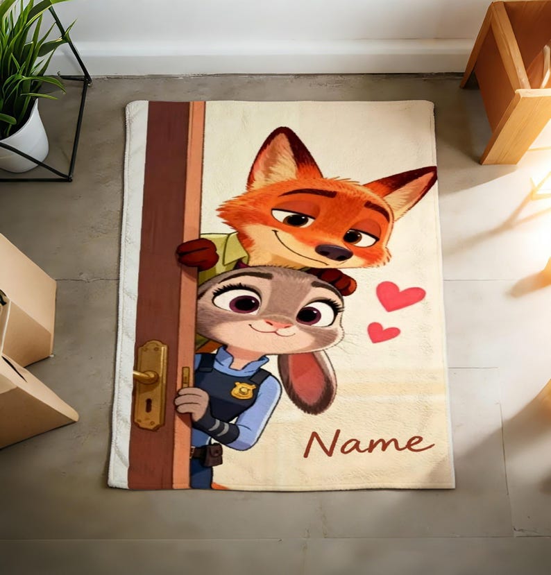 May include: A rectangular beige bath mat featuring cartoon characters Nick Wilde and Judy Hopps from Zootopia. Nick, an orange fox, peeks over a door with Judy, a gray rabbit, in a police uniform. Two red hearts and the word "Name" are also visible.