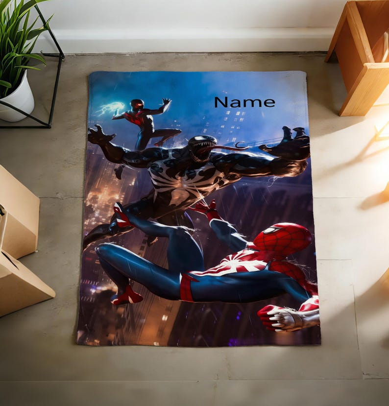 May include: A rectangular blanket featuring a graphic print of Spider-Man and Venom in a dynamic battle scene against a dark city background. The design includes a smaller figure in the upper left and the word Name printed in black text.
