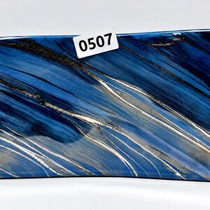 May include: A rectangular slab with a polished surface featuring swirling patterns of deep blue, navy, and black, accented by thin, diagonal silver-toned metallic veins. A small white rectangular tag with the black printed number 0507 is attached.