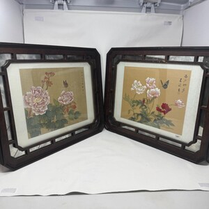 Puede incluir: Dos cuadros rectangulares enmarcados con pinturas florales sobre fondo beige. Cada pintura muestra peonías en flor en tonos rosa, blanco y rojo con hojas verdes y una mariposa. Los marcos son de madera de color marrón oscuro con recortes.