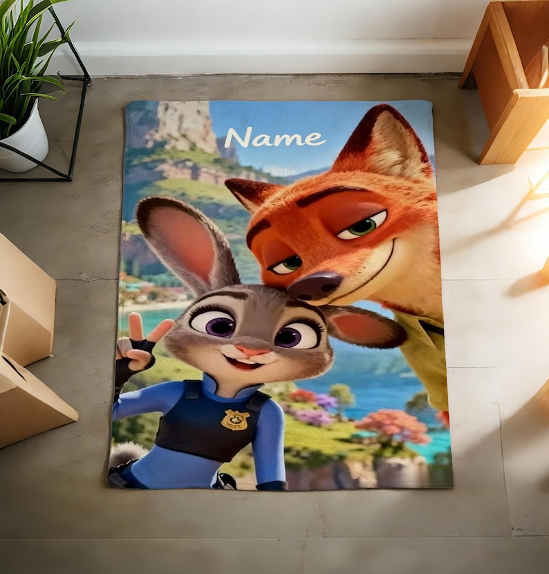May include: A rectangular blanket featuring the animated characters Judy Hopps and Nick Wilde from Zootopia. Judy, a gray rabbit, is in a police uniform, giving a peace sign. Nick, an orange fox, smiles. The word "Name" is at the top.
