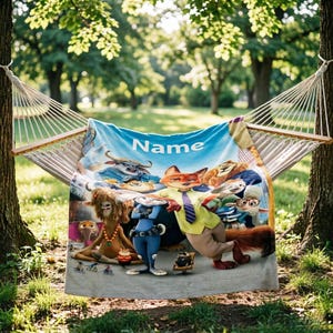 May include: A blue blanket with a cartoon image of characters from a movie, hanging on a hammock. The blanket has the word "Name" in white letters. The background is a green park with trees.