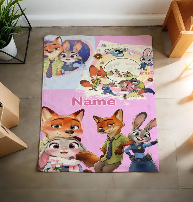May include: A rectangular fleece blanket featuring Zootopia characters Nick Wilde and Judy Hopps in various poses. The design includes a light pink background, a circular graphic with multiple characters, and the word Name printed in white text.