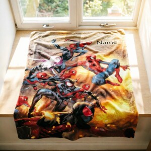 May include: A rectangular fleece blanket featuring a vibrant, multi-character Spider-Man graphic with various versions of the hero in action poses against a warm, golden-yellow background. The word Name is printed in black in the upper right corner.
