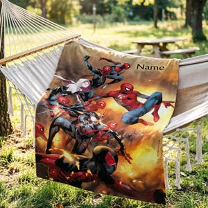 May include: A rectangular throw blanket featuring a vibrant graphic print of multiple Spider-Man characters in action poses against a fiery orange and yellow background. The word Name is printed in black text in the upper right corner of the blanket.