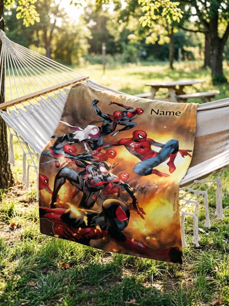 May include: A rectangular throw blanket featuring a vibrant graphic print of multiple Spider-Man characters in action poses against a fiery orange and yellow background. The word Name is printed in black text in the upper right corner of the blanket.
