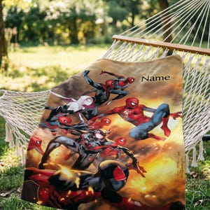 May include: A rectangular fleece blanket featuring a vibrant graphic print of multiple Spider-Man characters in action poses against a fiery orange and yellow background. The word Name is printed in black text in the upper right corner of the blanket.