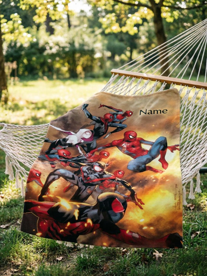 May include: A rectangular fleece blanket featuring a vibrant graphic print of multiple Spider-Man characters in action poses against a fiery orange and yellow background. The word Name is printed in black text in the upper right corner of the blanket.