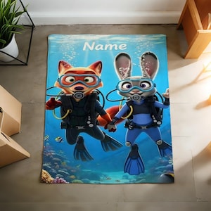 May include: A blue blanket featuring cartoon characters Nick Wilde and Judy Hopps from Zootopia, dressed in scuba gear. The blanket has the word "Name" printed at the top, with an underwater scene background.