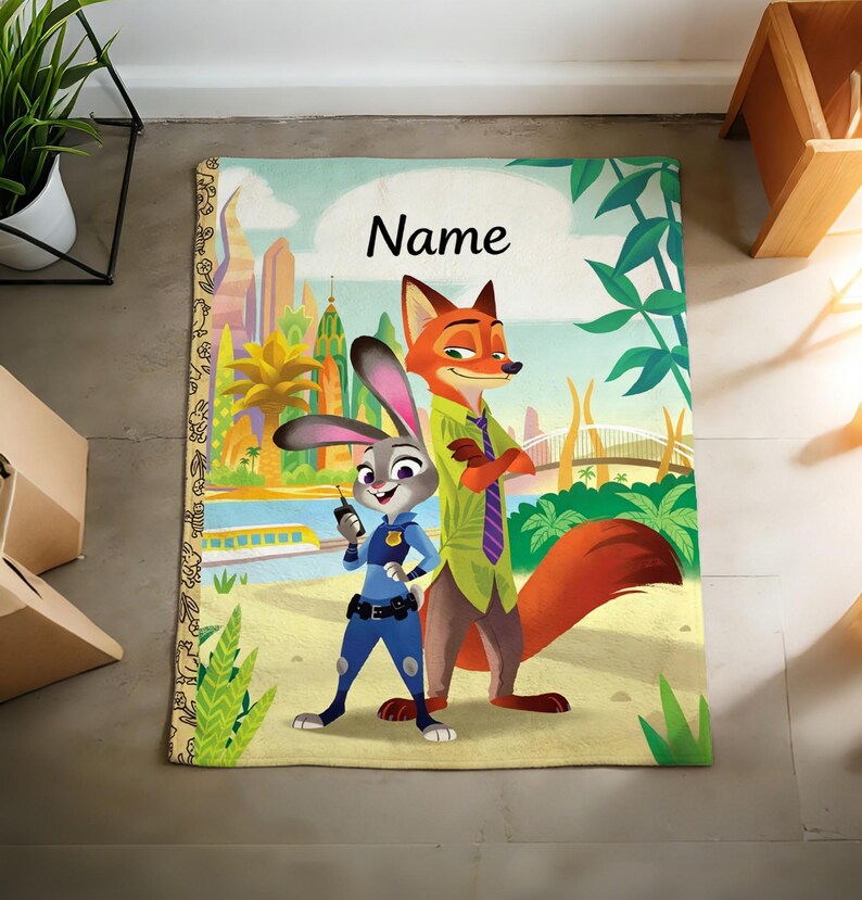 May include: A rectangular blanket featuring a colorful graphic of a rabbit police officer and a fox character standing in a city landscape. The word Name is printed in black script at the top center. The left border has a tan strip with small black line art.