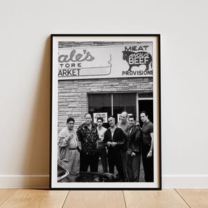 May include: Black and white framed print featuring a group of men posing in front of a storefront. The storefront sign reads "ale's TORE ARKET" and "MEAT ANGUS BEEF PROVISIONS". The image is a photograph.