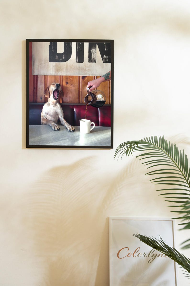 May include: Framed print featuring a dog yawning in a diner booth as coffee is poured into a mug. The diner sign is visible above the booth. The image has a vintage aesthetic with a red and wood-paneled booth.