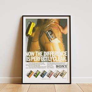 May include: Framed vintage advertisement for Sony audio tapes. The poster features a person in clear plastic pants with a yellow Walkman and a cassette tape. Text reads "NOW THE DIFFERENCE IS PERFECTLY CLEAR."