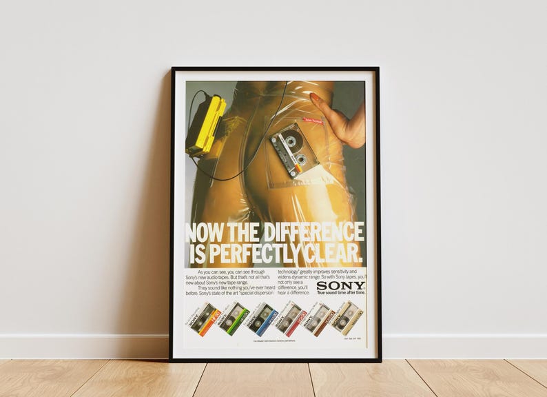May include: Framed vintage advertisement for Sony audio tapes. The poster features a person in clear plastic pants with a yellow Walkman and a cassette tape. Text reads "NOW THE DIFFERENCE IS PERFECTLY CLEAR."