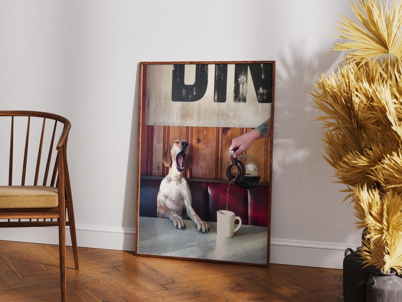 May include: A framed print featuring a dog yawning in a diner setting. The image includes a hand pouring coffee into a mug. The word "DIN" is visible at the top of the print. The dog is white and brown.
