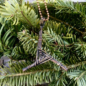 May include: A copper wire pendant necklace with a woven triangular design. The pendant is dark brown and has a copper chain.