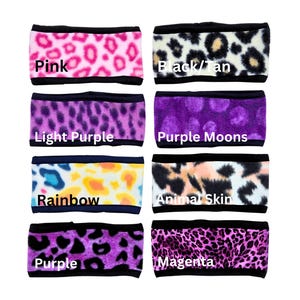 May include: Collection of eight headbands with various animal print patterns and colors, including pink, black/tan, light purple, purple moons, rainbow, animal skin, purple, and magenta. Each headband has a black border and the color name is printed on the headband.