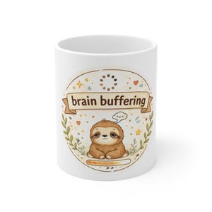 May include: White ceramic mug featuring a cartoon sloth with the text "brain buffering." The sloth is brown and sitting inside a decorative circle with stars, hearts, and leaves. The mug is a standard 11 oz size.