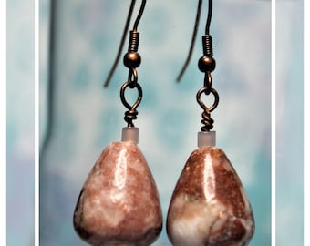 May include: A pair of dangle earrings with brown metal hooks and teardrop-shaped pink and white marble stones.