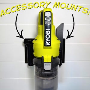 Puede incluir: Una aspiradora Ryobi amarilla y negra montada en una pared blanca con soportes de accesorios negros. El texto "ACCESSORY MOUNTS!" está en amarillo encima de la aspiradora. La aspiradora tiene un recipiente transparente para recoger el polvo.