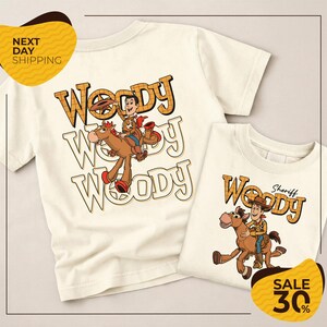 two white t-shirts with the character Woody from the Toy Story franchise. The t-shirts are displayed on a light background, and there are yellow and black text elements in the image.
