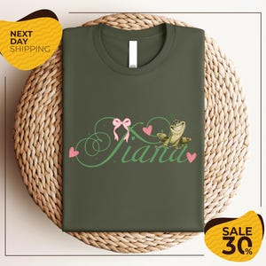a green t-shirt with a pink bow and the word "Panda" written on it, displayed on a woven basket.