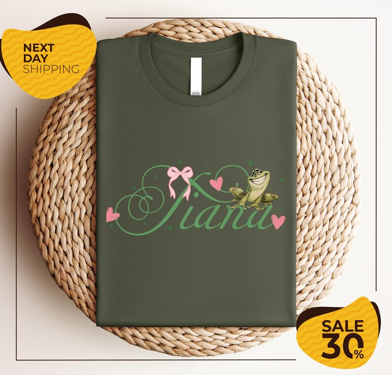 a green t-shirt with a pink bow and the word "Panda" written on it, displayed on a woven basket.