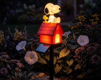 May include: A solar-powered garden light featuring a white Snoopy figure and a yellow Woodstock figure sitting on top of a red doghouse. The doghouse glows with an internal light, and a small solar panel is attached to the side of the black stake.