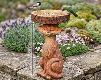 May include: A whimsical, brown, carved bird feeder with a fox base and a wooden bowl. The feeder is 20 cm tall and has a bird perched on the rim and a hummingbird drinking from it. The feeder is placed on a stone wall in a garden setting.