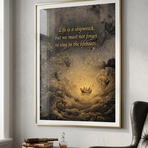 Op de afbeelding: Ingelijste kunstafdruk met de quote: "Het leven is een schipbreuk, maar we moeten niet vergeten te zingen in de reddingsboten." De afbeelding toont een boot op een stormachtige zee, met gouden tinten en een dramatische lucht. De lijst is goud.