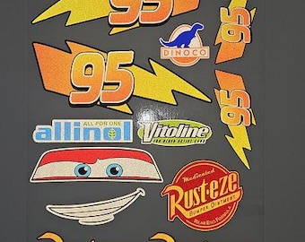 Peut inclure: Une planche d'autocollants présentant divers motifs, dont le nombre 95 sur des éclairs jaunes, un logo de dinosaure bleu Dinoco, les textes Allinol et Vitoline, une paire d'yeux de voiture, une bouche souriante et plusieurs logos Rust-eze.