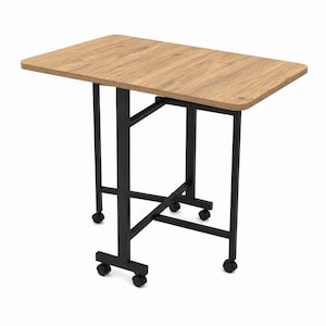 Op de afbeelding: Een rechthoekige, lichtbruine tafel met een houtnerf afwerking. De tafel heeft zwarte metalen poten en staat op wielen. De tafel is ongeveer 76 cm lang en 51 cm breed.