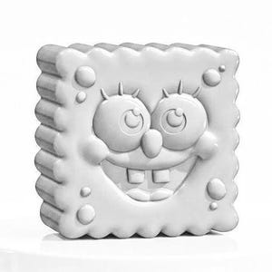 May include: A white, three-dimensional sculpture of the cartoon character SpongeBob SquarePants. The sculpture has a square shape with a wavy border and features SpongeBob's smiling face, complete with eyes, eyelashes, and teeth. The sculpture is on a white surface.
