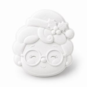 May include: A white, matte-finish cookie cutter shaped like the face of a grandmother figure wearing round glasses. The design features embossed details including a hair bun, a small holly leaf and berry accent, and a smiling expression.